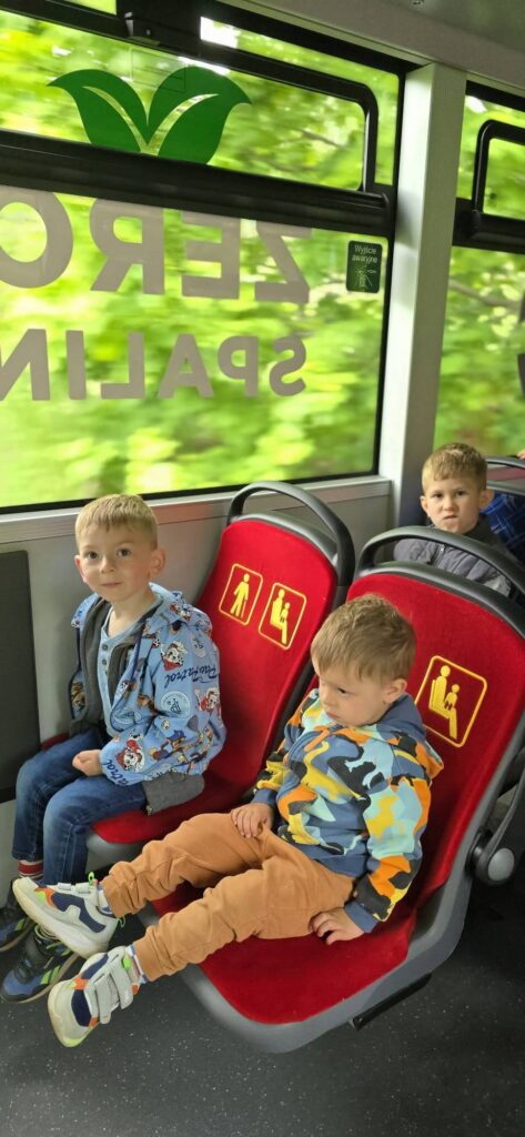 Przedszkolaki siedzą w fotelikach we wnętrzu autobusu wodorowego MZUK.